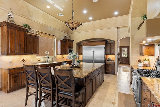 714 Washington Ct, Grand Junction, CO 81507 - kitchen featuring arched walkways, built in appliances, a high ceiling, a kitchen island, and light tile patterned floors