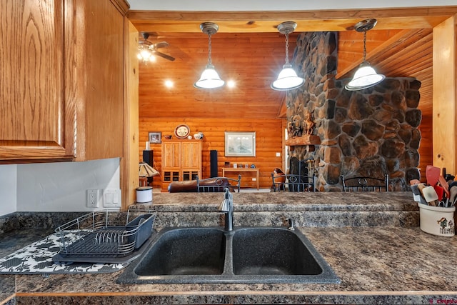 kitchen with a sink, log walls, decorative light fixtures, and dark countertops