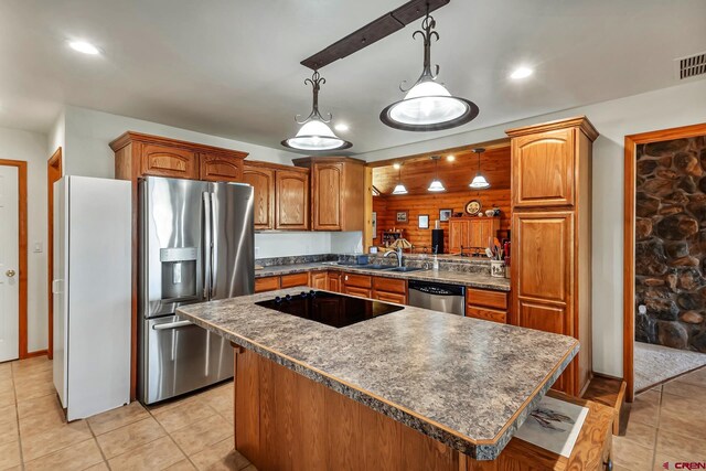 kitchen with dark countertops, hanging light fixtures, a sink, a center island, and stainless steel appliances