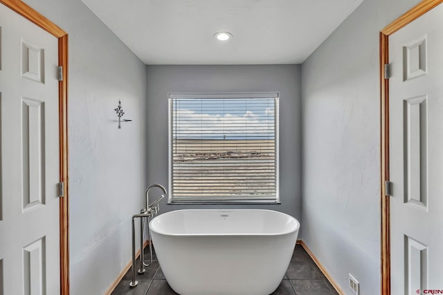 bathroom featuring a freestanding tub, baseboards, tile patterned flooring, and visible vents