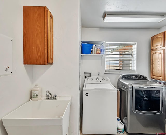 clothes washing area with a sink, cabinet space, and washing machine and clothes dryer