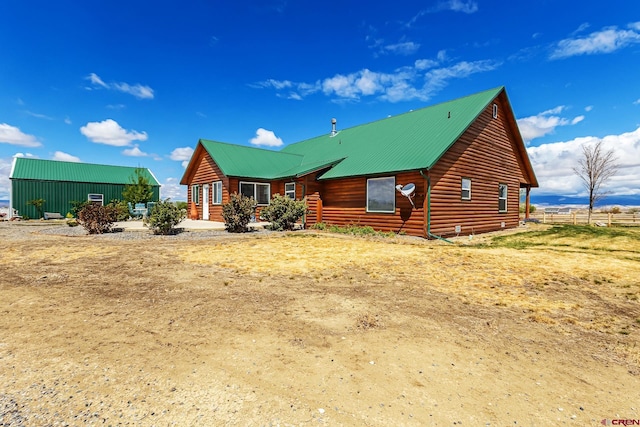 view of front of house with log veneer siding, fence, and metal roof