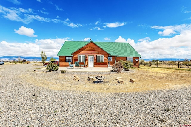 rear view of property with a patio, metal roof, and faux log siding