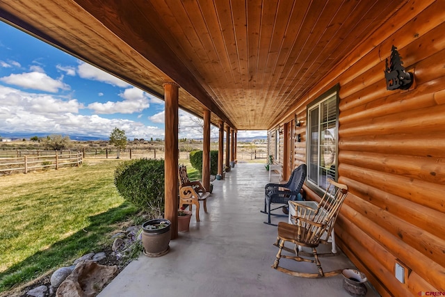 view of patio featuring fence, a porch, and a rural view