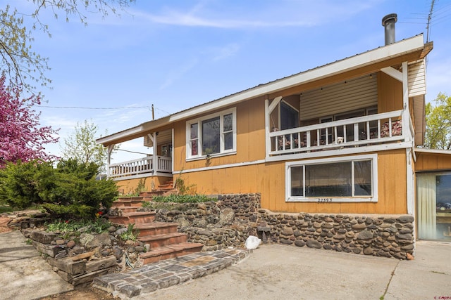 view of front of property with metal roof, a balcony, and stairs