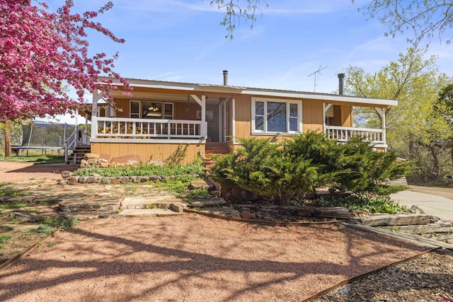 ranch-style home with a porch, a trampoline, and stairs