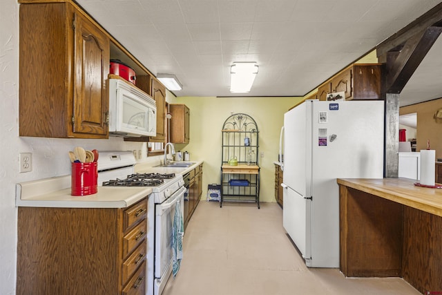 kitchen with light countertops, brown cabinets, white appliances, and a sink