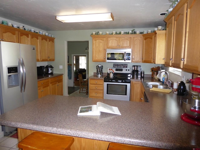 kitchen with a breakfast bar, stainless steel appliances, a peninsula, and a sink