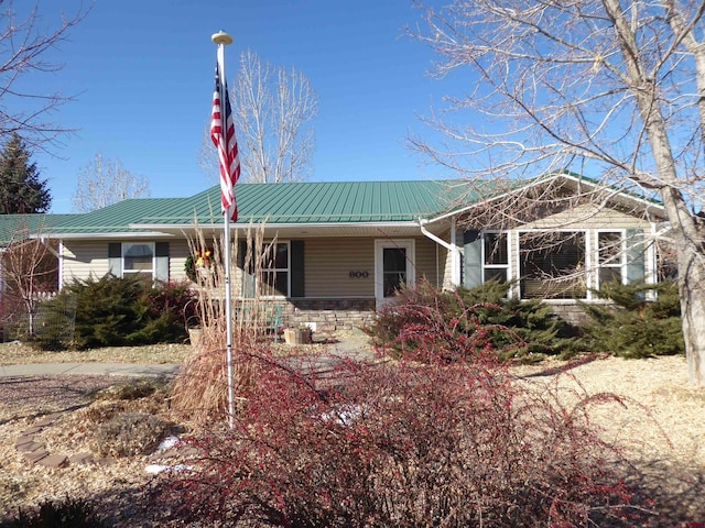 single story home with metal roof and stone siding