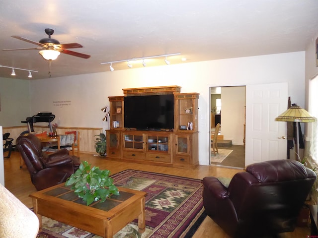 living area with track lighting, wood finished floors, and ceiling fan