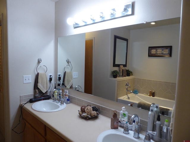 bathroom featuring a sink, double vanity, and a bath