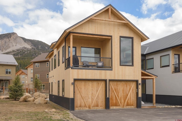 view of front of home featuring a balcony, driveway, an attached garage, and a mountain view