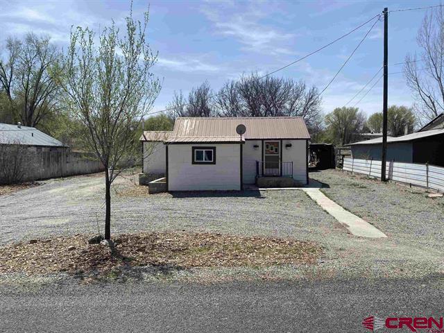 bungalow-style home featuring fence and metal roof