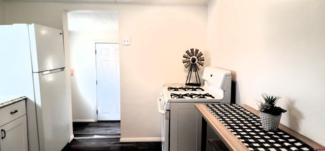kitchen with light countertops, dark wood-type flooring, baseboards, and white appliances