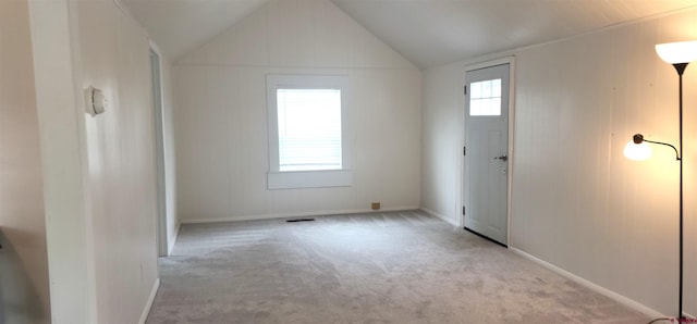 carpeted spare room with lofted ceiling, baseboards, and visible vents