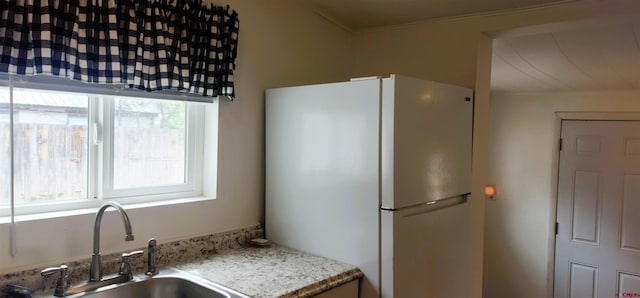 kitchen with freestanding refrigerator, light stone counters, plenty of natural light, and a sink
