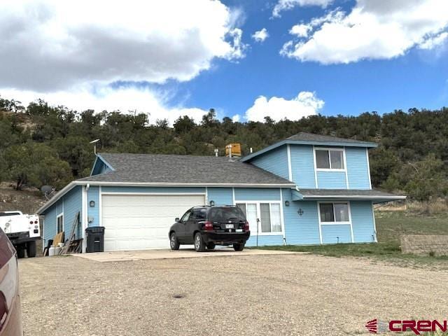 30022 Rd L, Mancos, CO 81328 - view of front of house with driveway, a forest view, and a garage