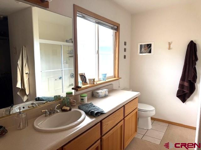 30022 Rd L, Mancos, CO 81328 - bathroom with toilet, baseboards, a shower stall, tile patterned flooring, and vanity