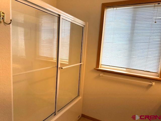 30022 Rd L, Mancos, CO 81328 - full bathroom with baseboards and shower / bath combination with glass door