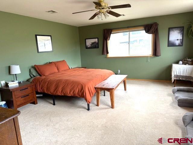 30022 Rd L, Mancos, CO 81328 - bedroom featuring a ceiling fan, light carpet, baseboards, and visible vents
