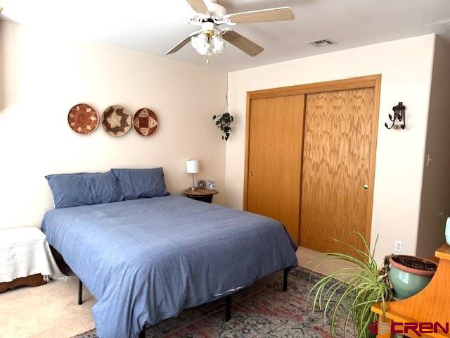 30022 Rd L, Mancos, CO 81328 - bedroom with a closet, visible vents, a ceiling fan, and carpet