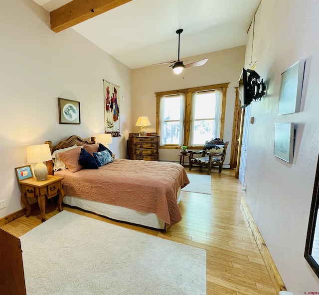 bedroom featuring light wood finished floors, baseboards, a ceiling fan, and beamed ceiling