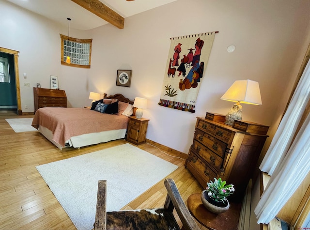 bedroom featuring baseboard heating, wood finished floors, baseboards, and beamed ceiling