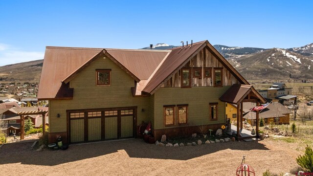 view of front of home with an attached garage, a mountain view, driveway, and metal roof
