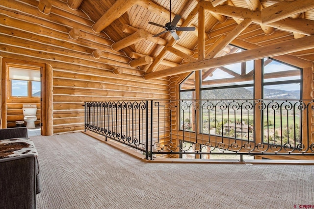 interior space featuring a ceiling fan, high vaulted ceiling, beamed ceiling, wooden ceiling, and rustic walls