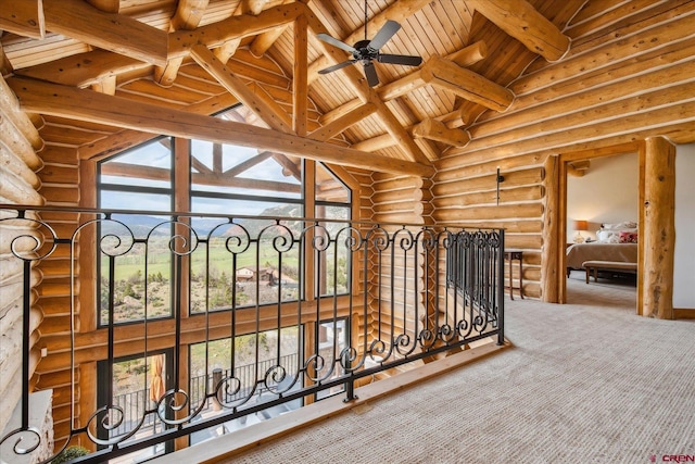 interior space featuring carpet, log walls, ceiling fan, wood ceiling, and lofted ceiling with beams