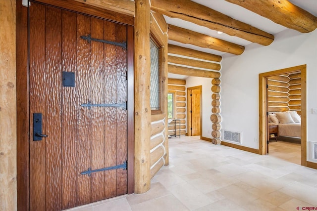 hallway featuring baseboards, beamed ceiling, rustic walls, and visible vents