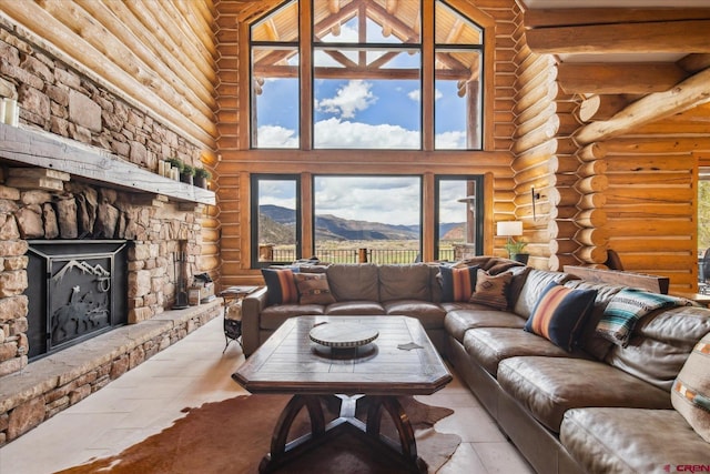 living area with a stone fireplace, log walls, a mountain view, and a high ceiling