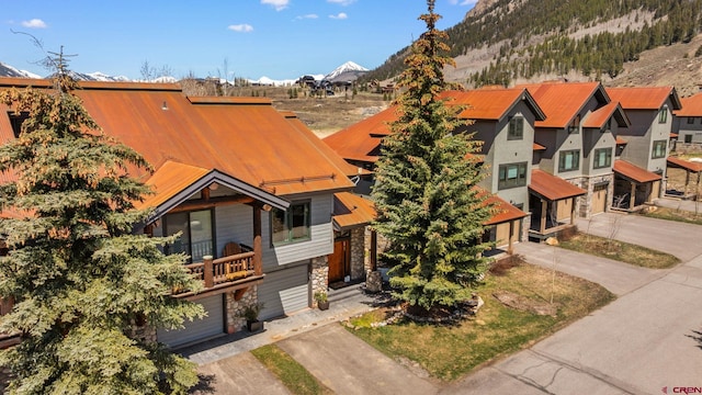 view of front of house featuring stone siding, a residential view, a mountain view, and driveway