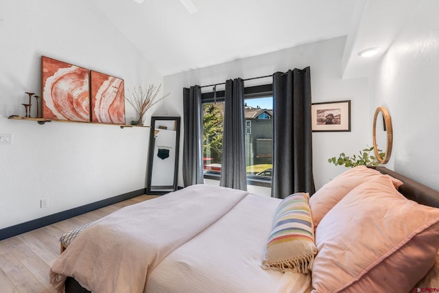 bedroom featuring lofted ceiling, baseboards, and wood finished floors