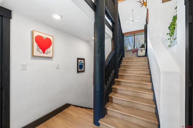 stairway featuring wood finished floors and a ceiling fan