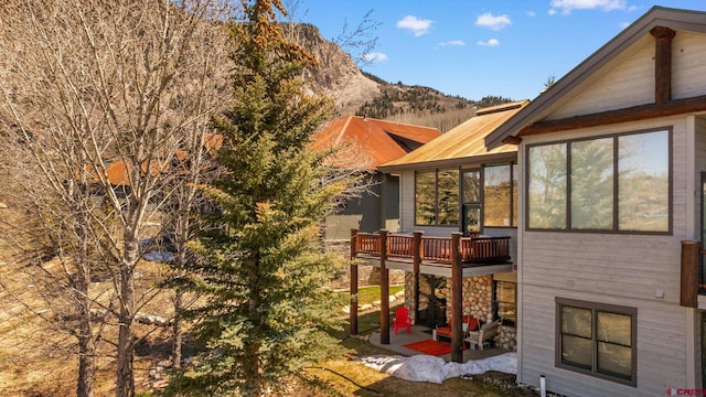 view of side of property with a patio, a sunroom, and a mountain view