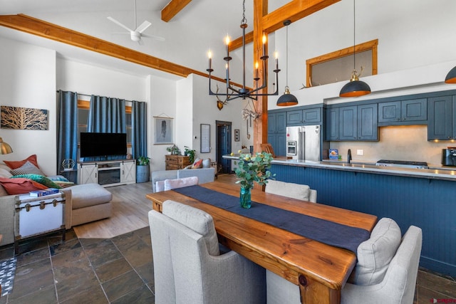 dining space with beamed ceiling, high vaulted ceiling, a ceiling fan, and stone finish floor