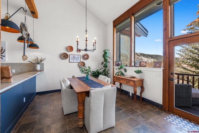 dining space featuring stone tile floors, baseboards, and an inviting chandelier