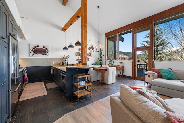 living area with a wealth of natural light, a notable chandelier, beamed ceiling, and stone tile flooring