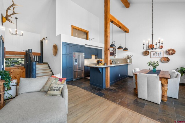 kitchen with a peninsula, high quality fridge, high vaulted ceiling, a chandelier, and blue cabinetry