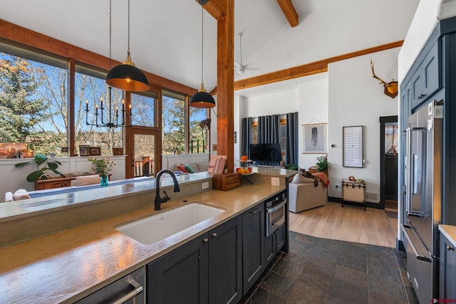 kitchen featuring a sink, open floor plan, lofted ceiling with beams, light countertops, and high end refrigerator