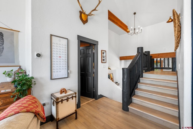 entryway featuring stairway, a chandelier, high vaulted ceiling, and wood finished floors