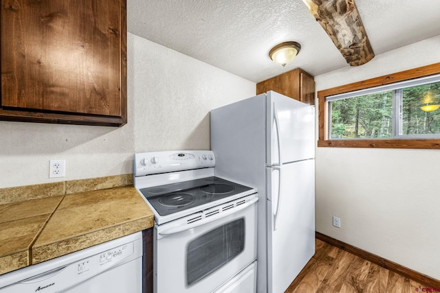 kitchen with a textured ceiling, baseboards, white appliances, light wood-style floors, and a textured wall
