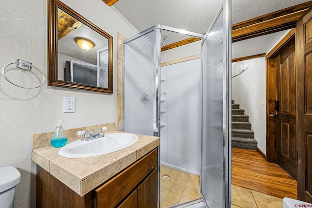 bathroom with a textured ceiling, toilet, a shower stall, and a textured wall