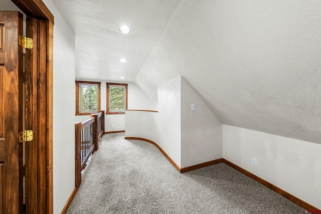 bonus room with carpet, a textured ceiling, baseboards, and lofted ceiling