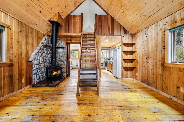 interior space with a wood stove, wooden walls, and wood-type flooring