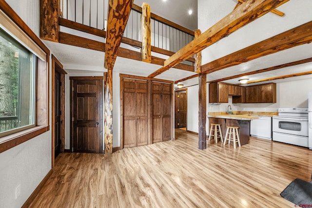 kitchen with white appliances, a kitchen bar, a peninsula, light wood-style floors, and light countertops