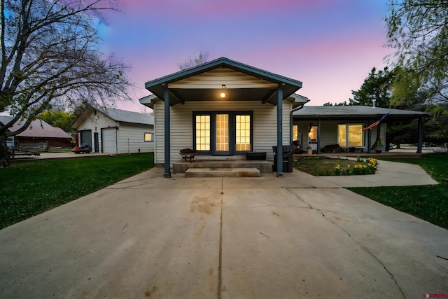 view of front of property with covered porch, a yard, and a garage