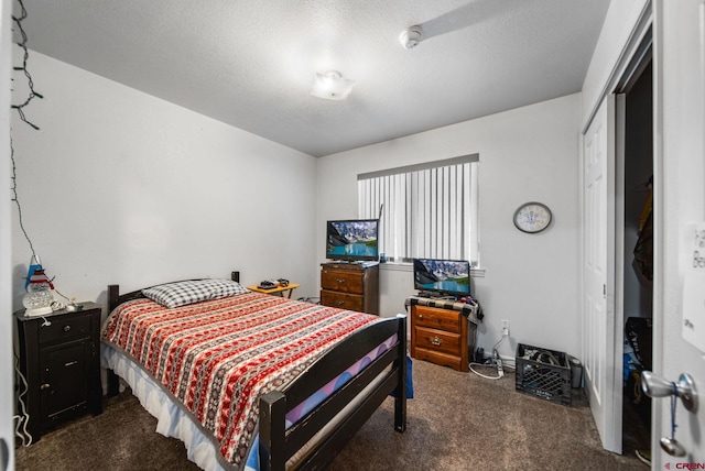 bedroom featuring dark carpet, a closet, and a textured ceiling