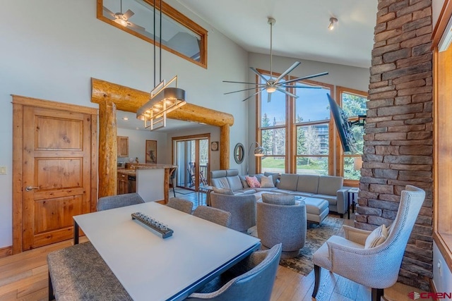 dining area with light wood-style flooring, ceiling fan, and high vaulted ceiling